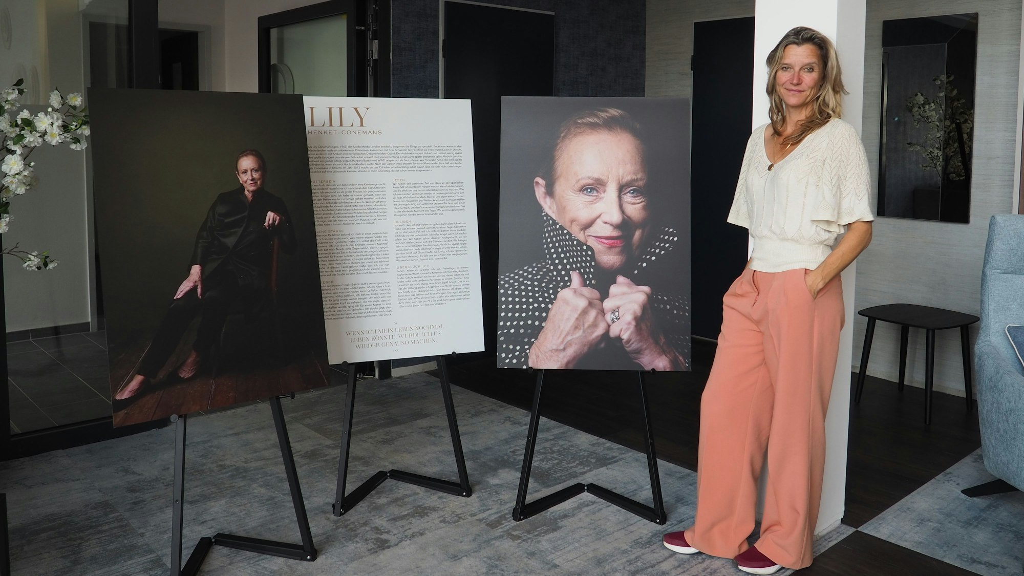 Eine Frau steht neben Plakaten.