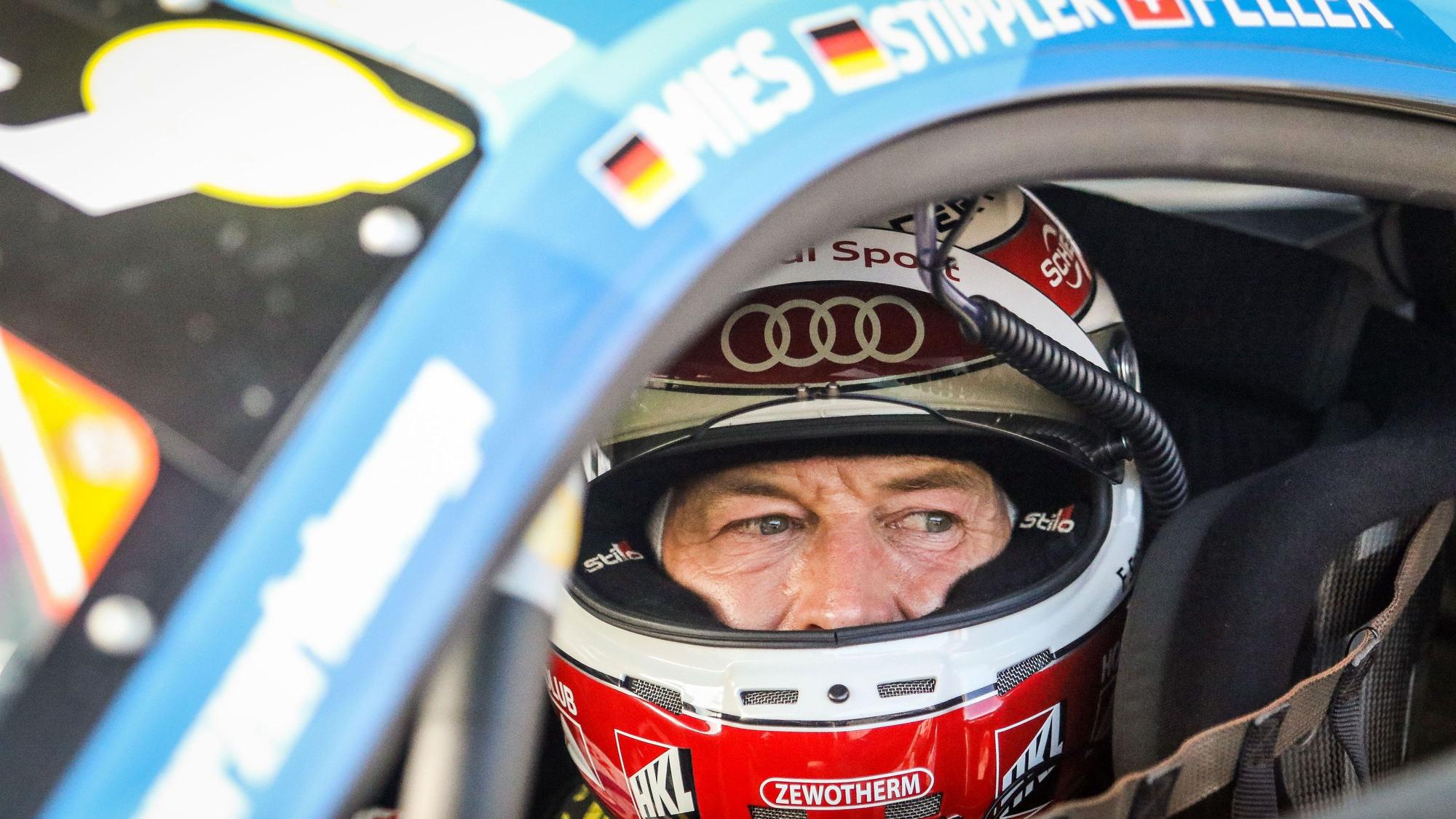 Rennfahrer Frank Stippler sitzt, mit geöffnetem Visier, in seinem Rennwagen.