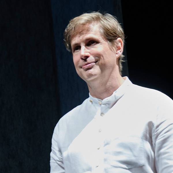 Der Schriftsteller Daniel Kehlmann steht auf der Bühne im Berliner Ensemble. Er trägt ein weißes Hemd und lächelt.