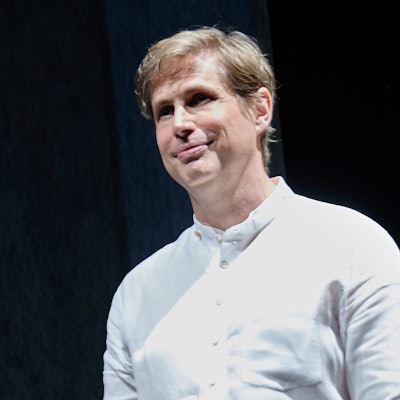 Der Schriftsteller Daniel Kehlmann steht auf der Bühne im Berliner Ensemble. Er trägt ein weißes Hemd und lächelt.