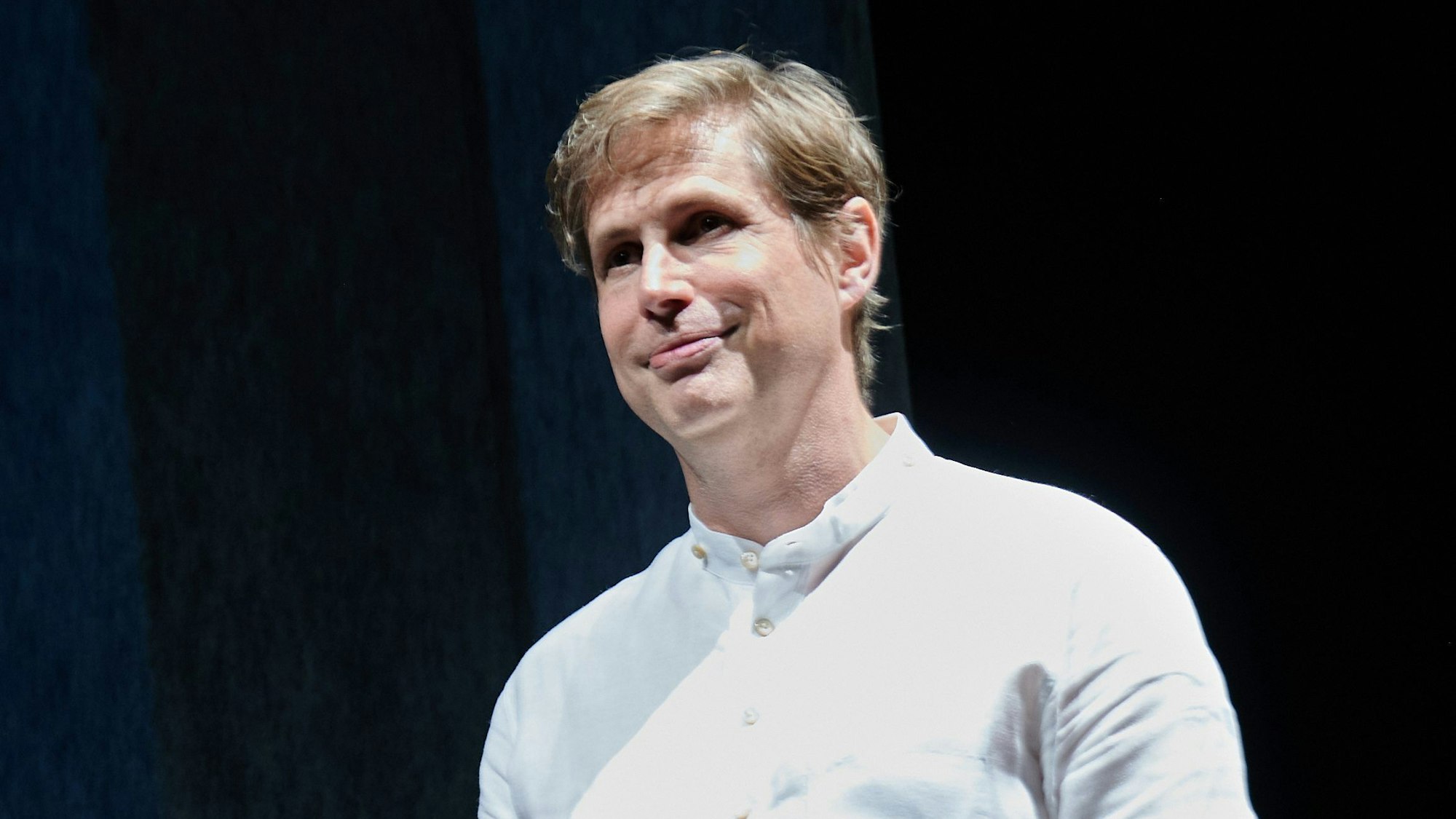 Der Schriftsteller Daniel Kehlmann steht auf der Bühne im Berliner Ensemble. Er trägt ein weißes Hemd und lächelt.
