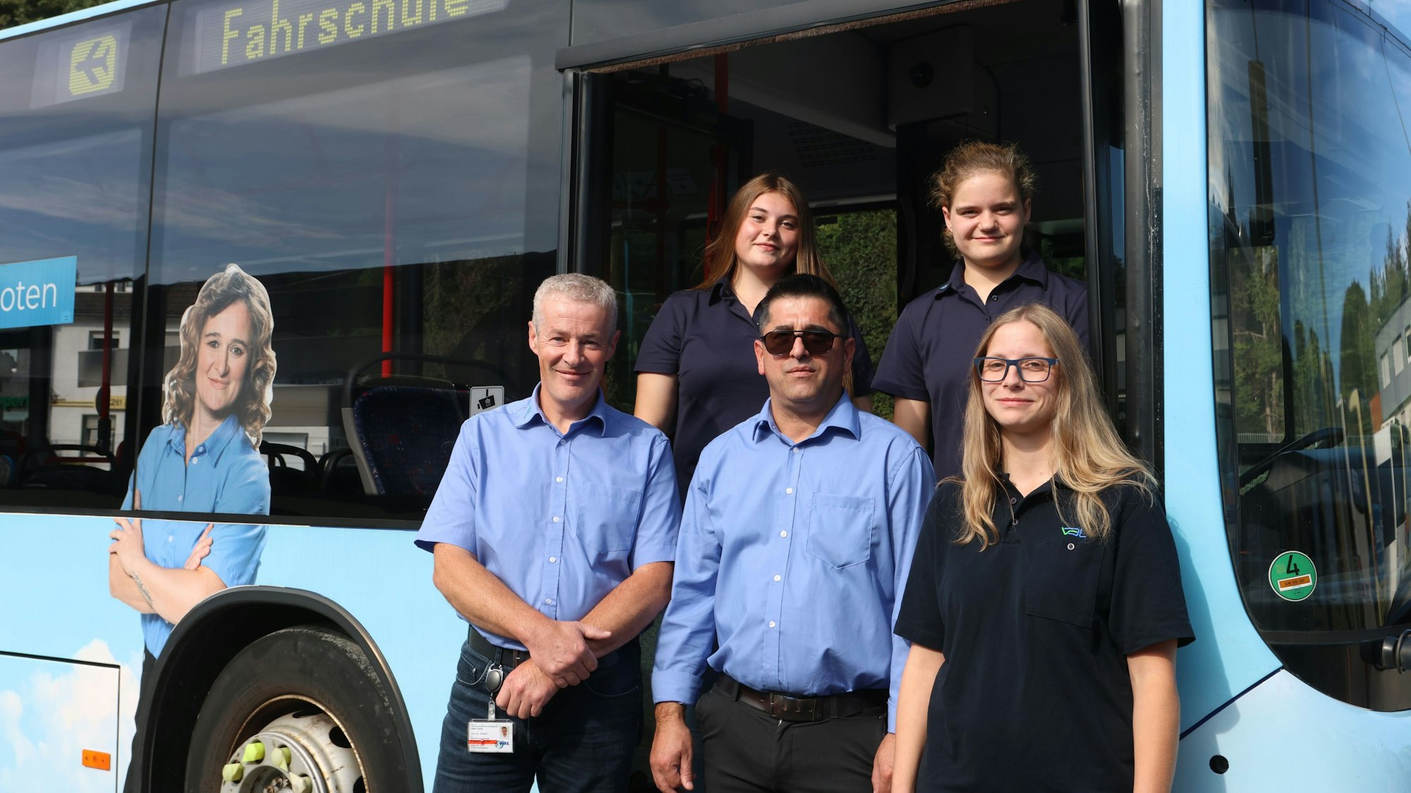 Mehrere Personen stehen in der Türe eines Linienbusses. Auf diesem steht „Fahrschule“.