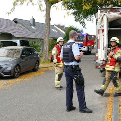 Feuerwehrleute und Polizeibeamte hinter dem Müllwagen.