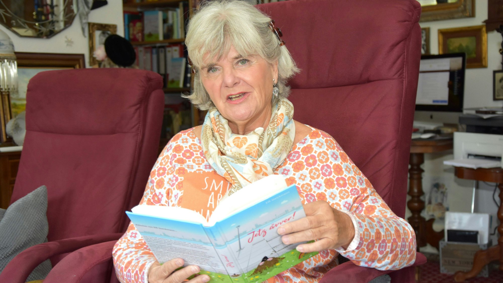 Die Mundartautorin Elfi Steickmann sitzt in einem großen Sessel und liest aus ihrem neuen Buch „Jetz ävver“ vor.