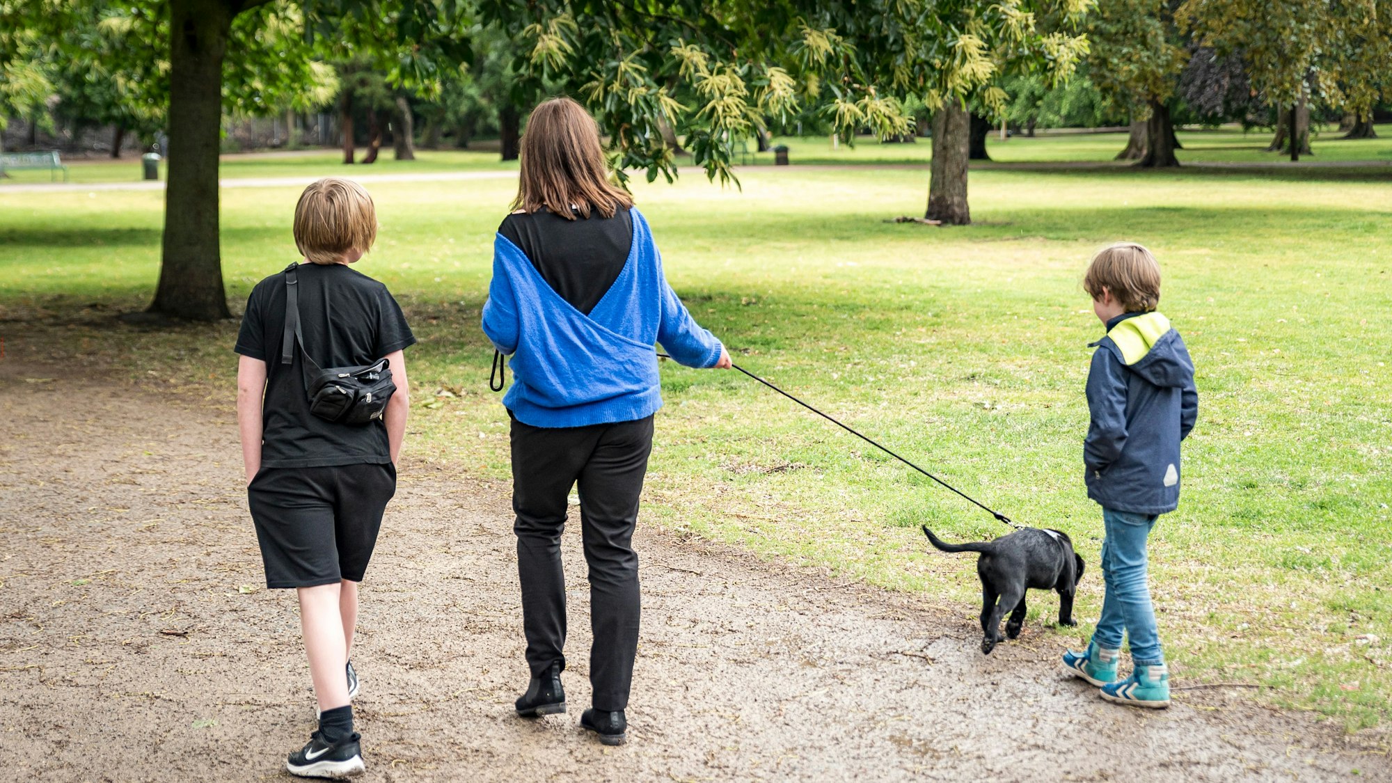 Eine Mutter ist mit ihren beiden Kindern und kleinem Hund unterwegs.
