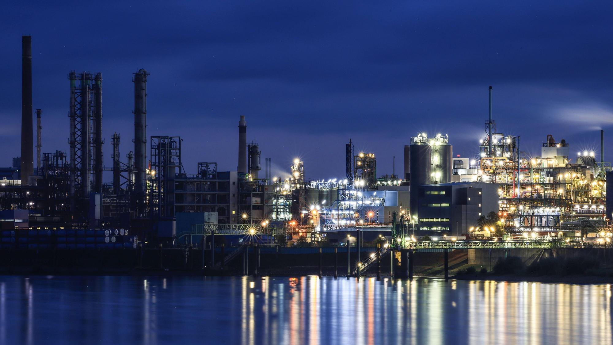 Lichter von Werksanlagen auf dem Chempark in Leverkusen spiegeln sich im Rhein.