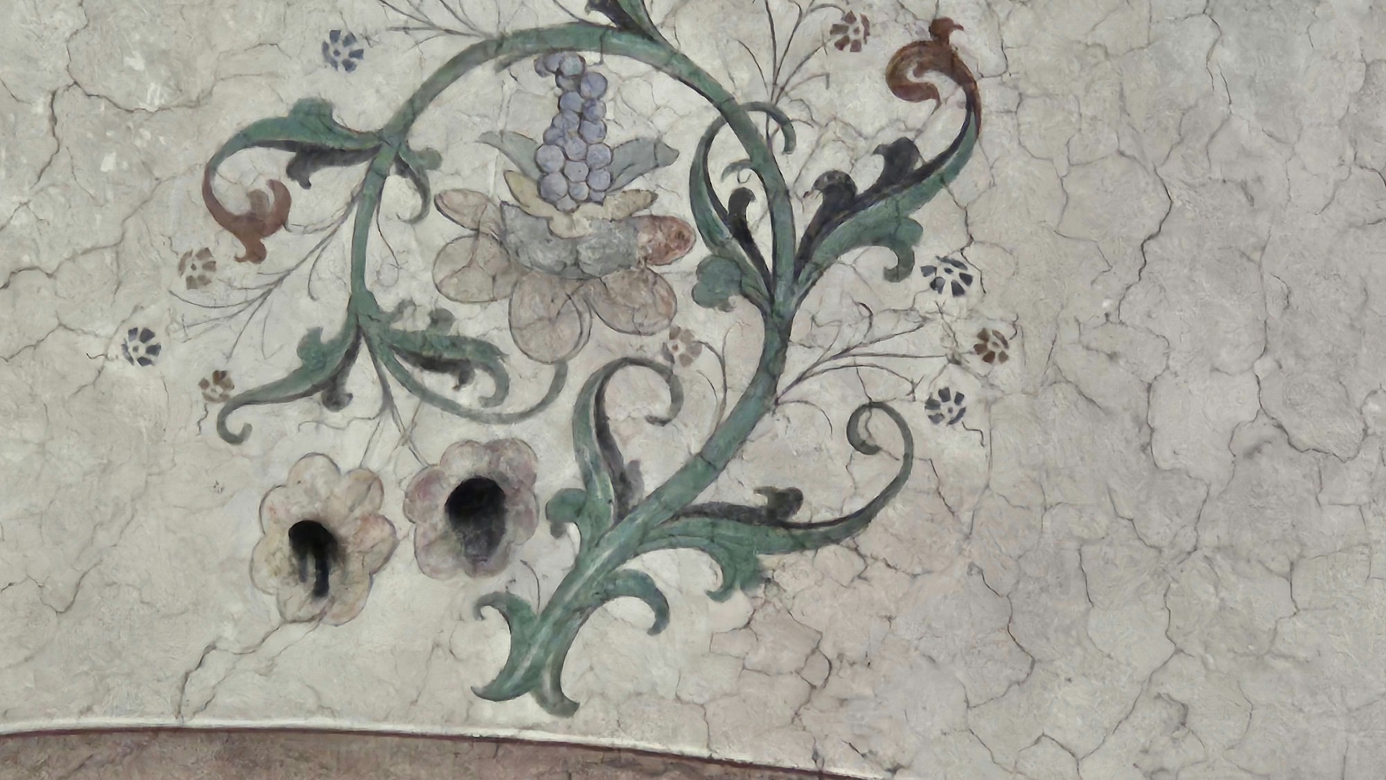 Zwei Blütenkelche in einer Deckenmalerei bestehen aus Löchern.