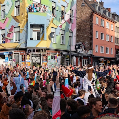 Menschenmassen jubeln verkleidet auf der Straße.