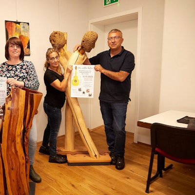 In einem Raum mit Holzskulpturen stehen die Veranstalter des Benefizkonzerts. Gaby Hess (v.l.), Lotte Ackermann-Vandeweyer, Serpil Yildiz und Yasin Yildiz halten die Plakate in den Händen.
