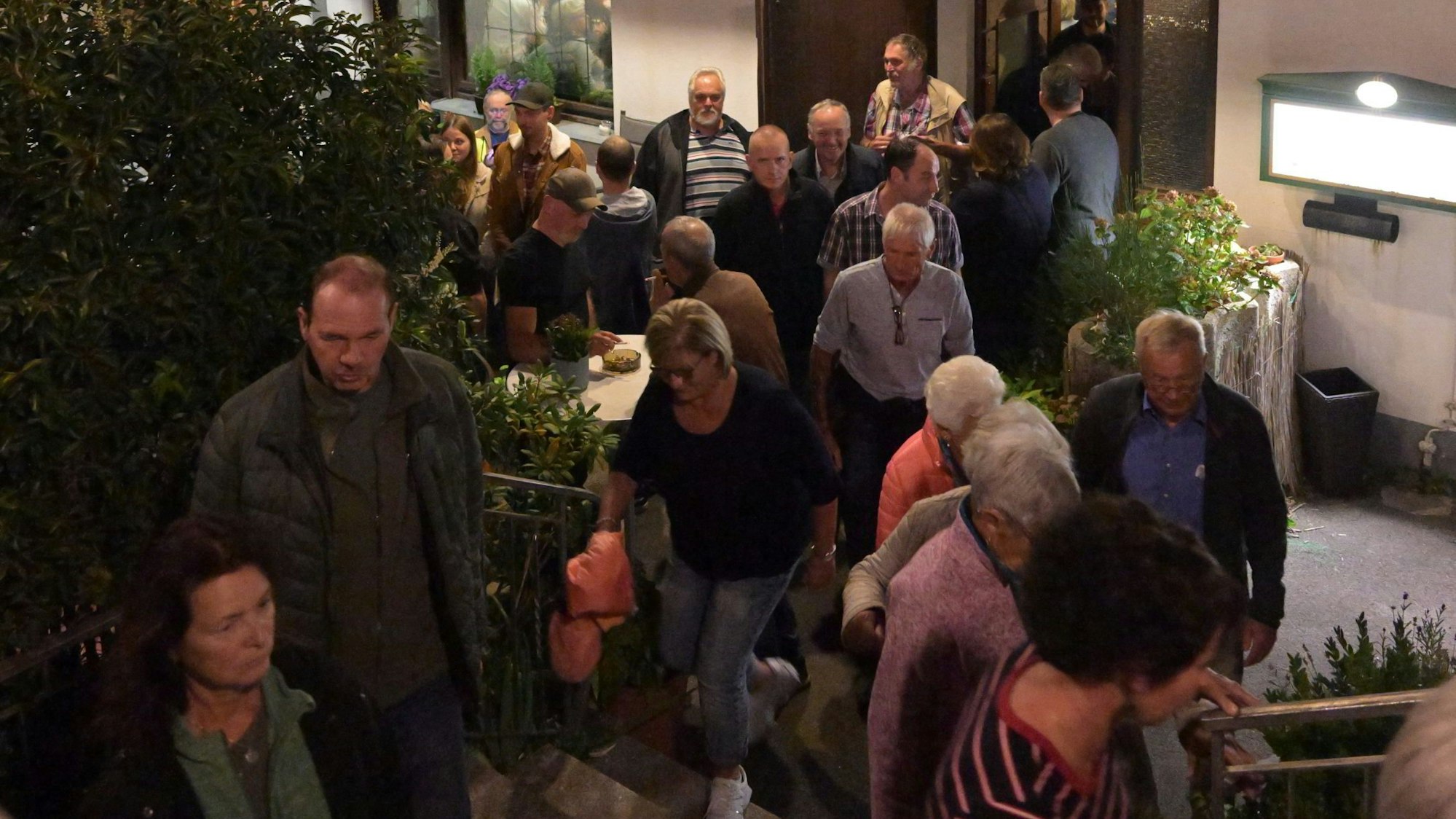 Eine Menschentraube steht vor einem Gebäude.