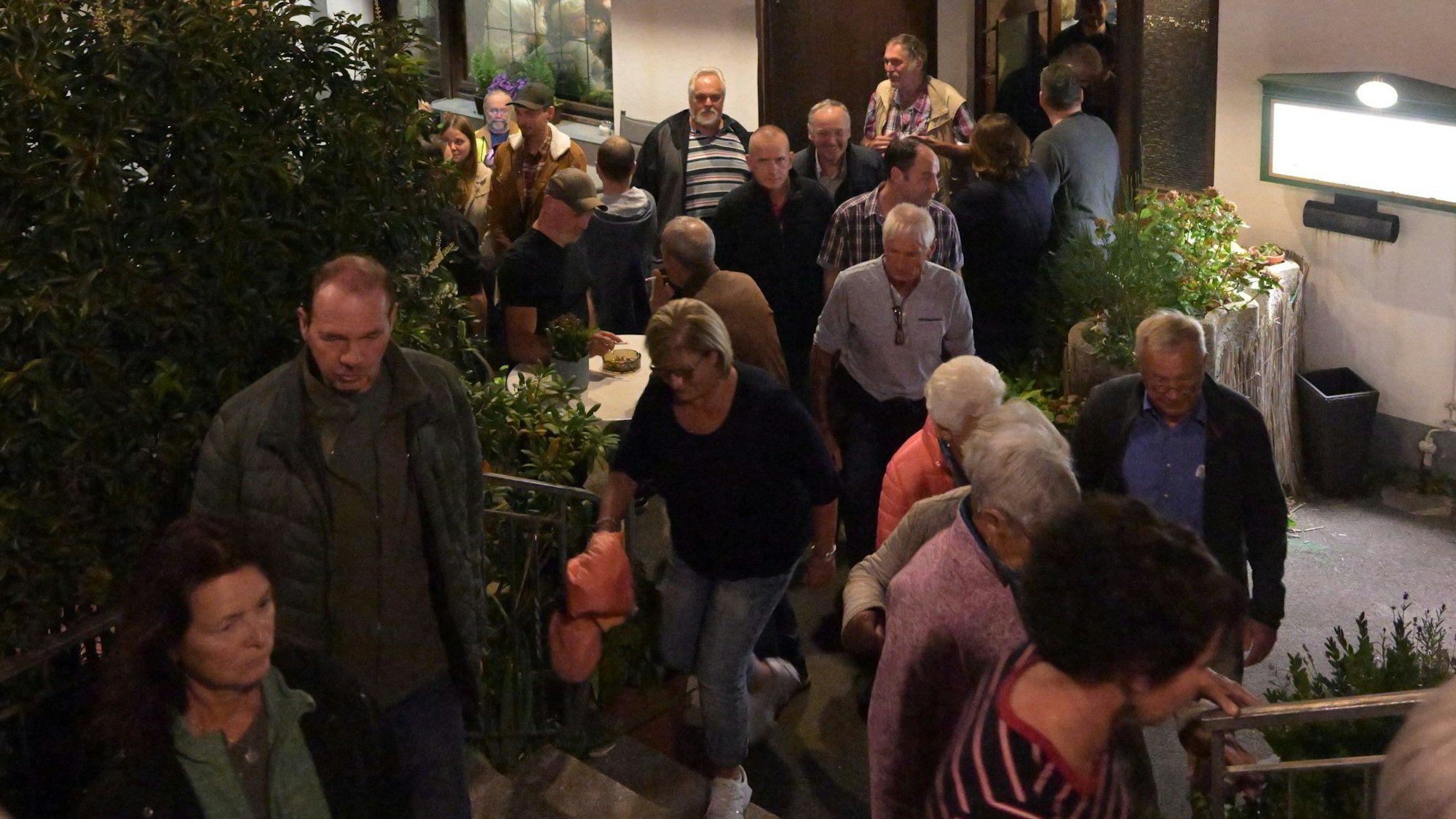 Eine Menschentraube steht vor einem Gebäude.