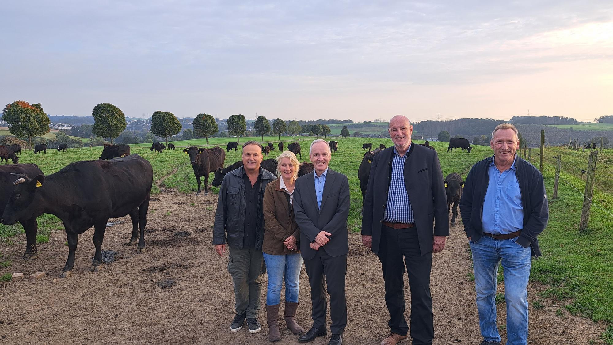 Das Foto zeigt fünf Vertreter der Kooperationspartner auf einer Weide mit Kühen.