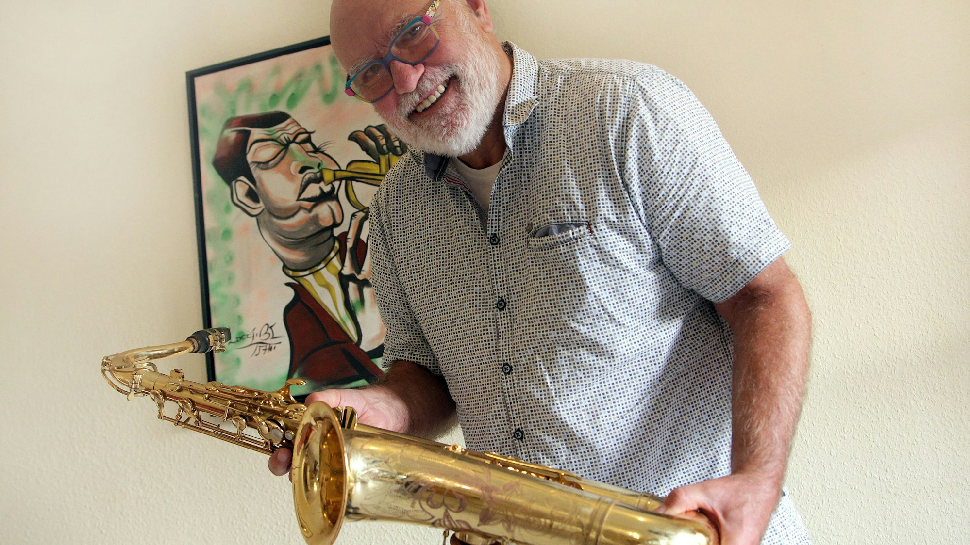 Ein Mann hält ein Saxophon.