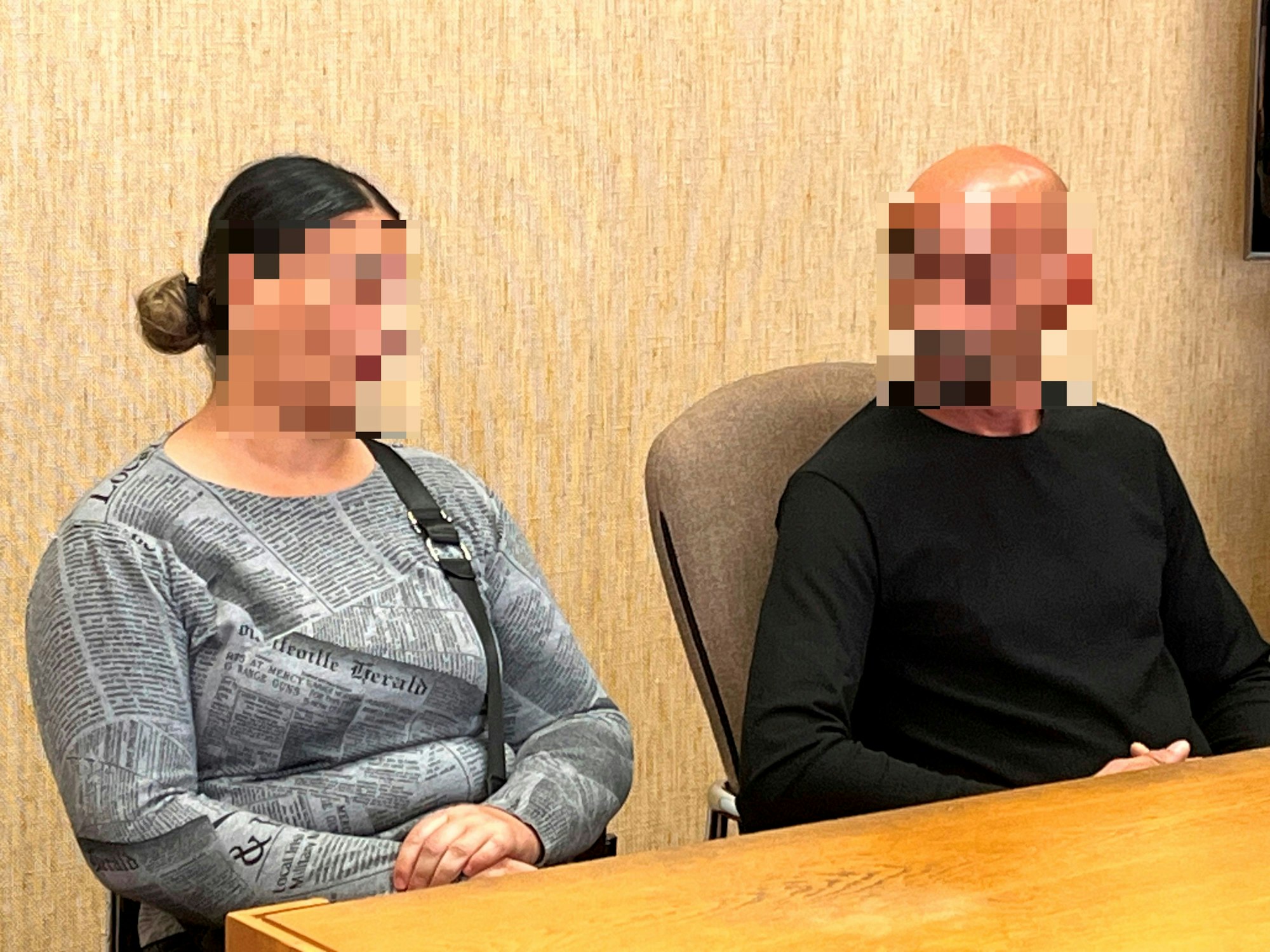 Zwei verpixelte Menschen sitzen auf der Anklagebank.