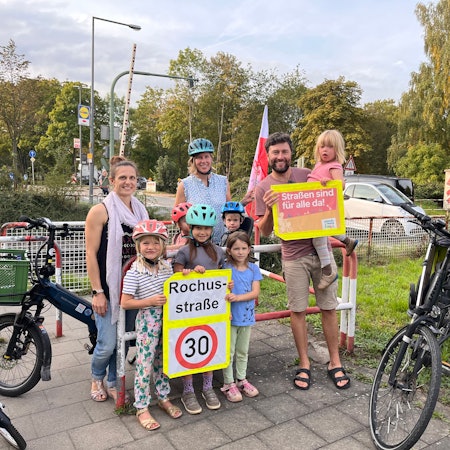 Eltern stehen vor einem Bahnübergang.