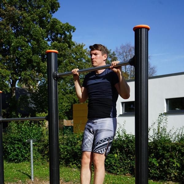 Ein Mann macht Klimmzüge an einer Stange.