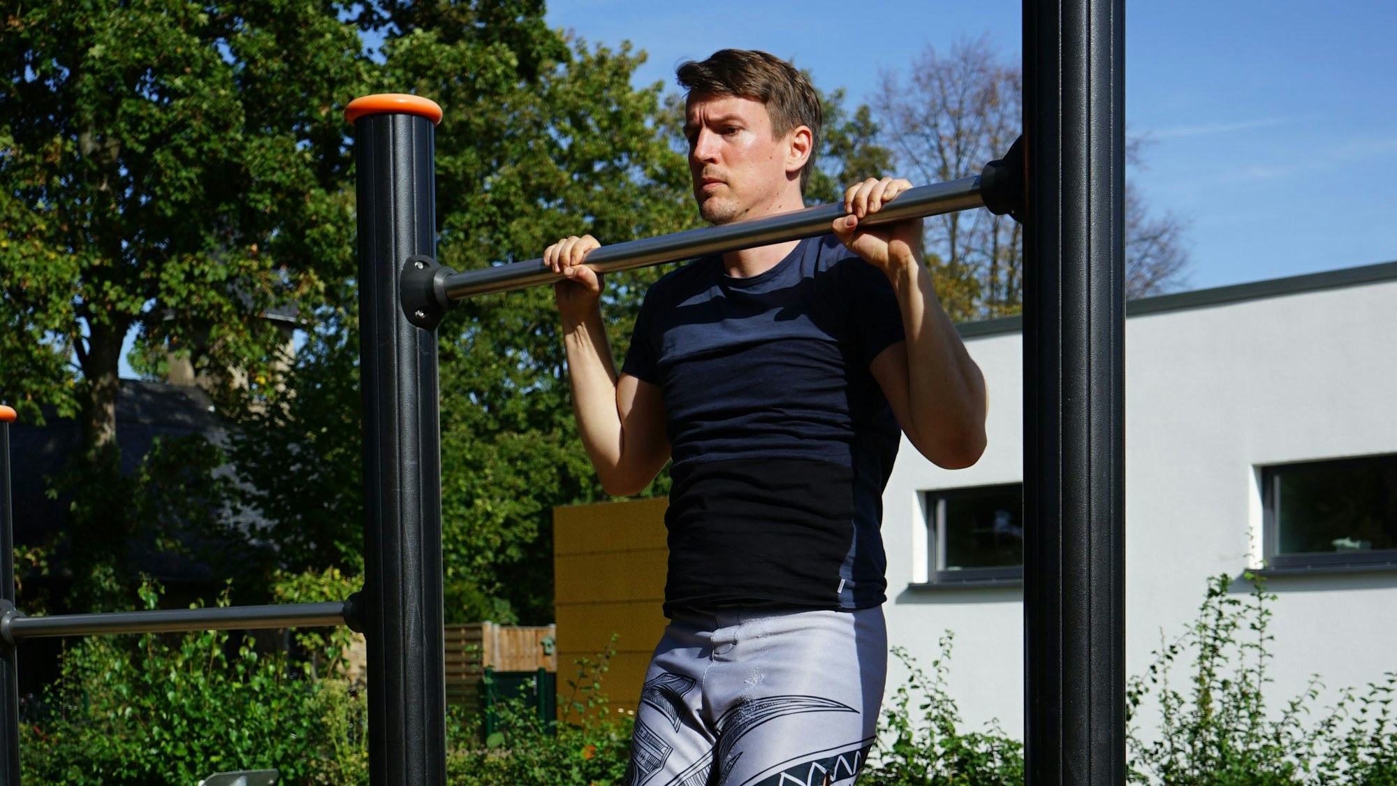 Ein Mann macht Klimmzüge an einer Stange.