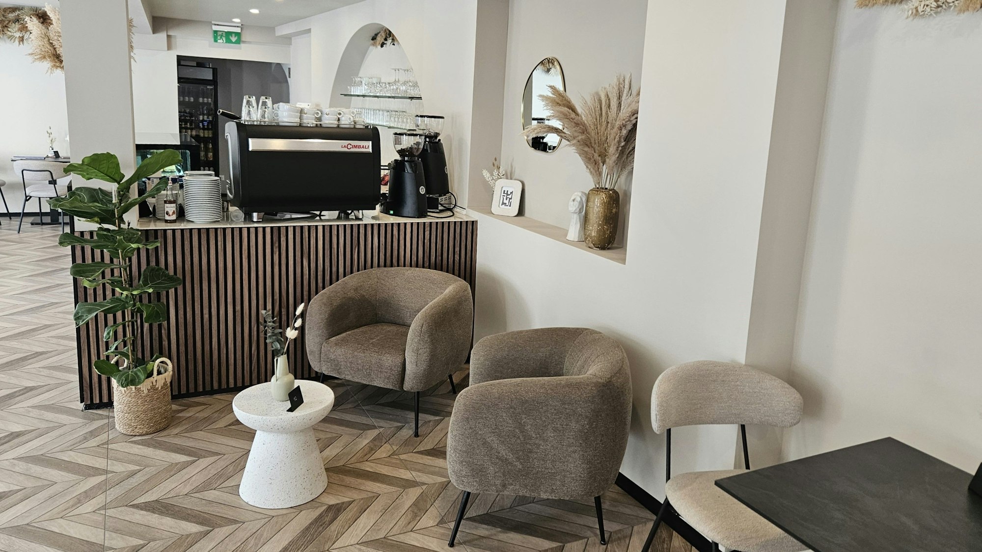 Blick in das Cafe mit gepolsterten Sesseln und Stühlen und einem Teil der Theke.