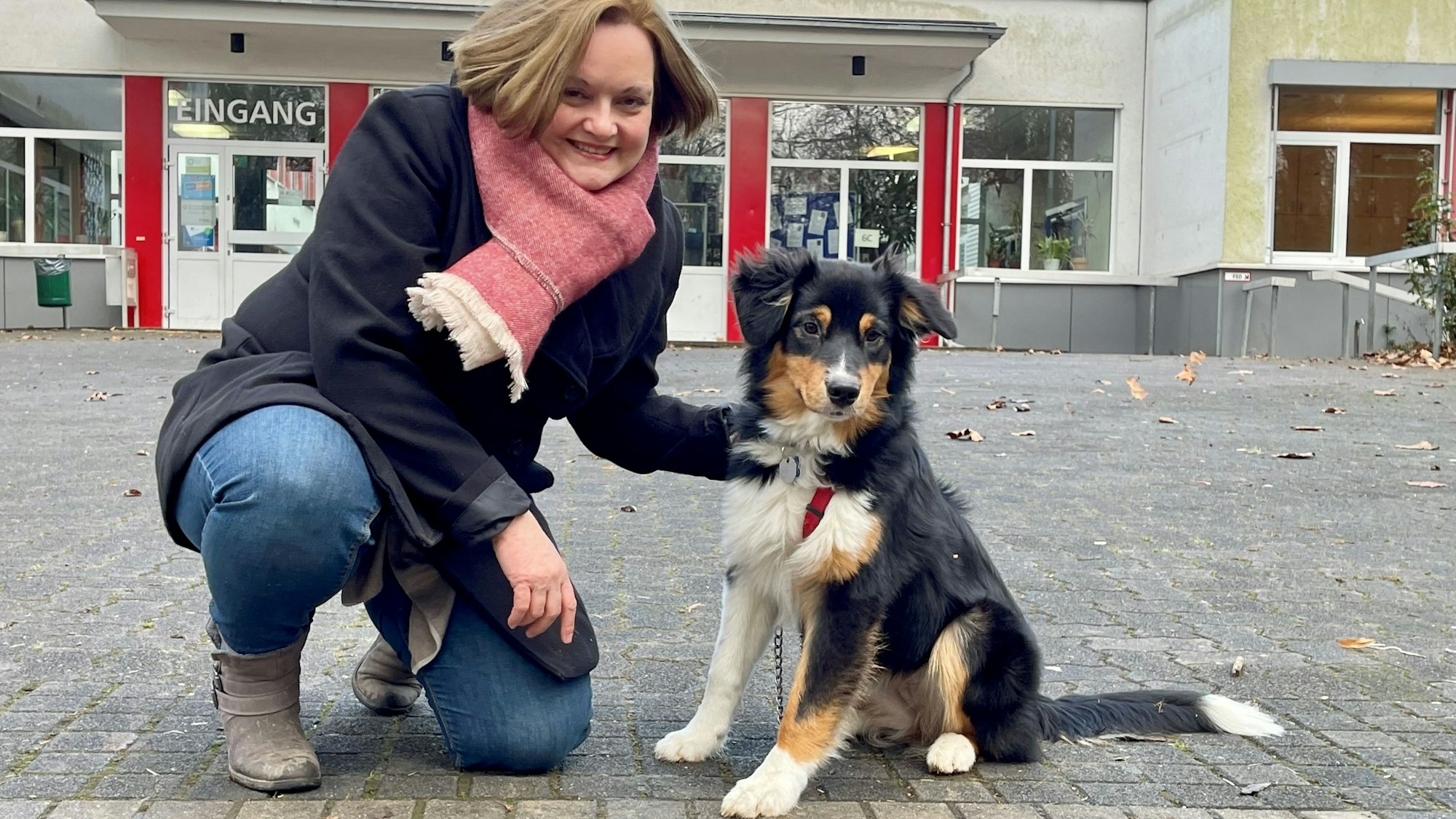 Lotta ist eine Australian Shepherd-Hündin mit schwarzem, braunem und weißem Fell. Neben ihr kniet ihre Besitzerin, die Diplom-Pädagogin Anna Köstering.