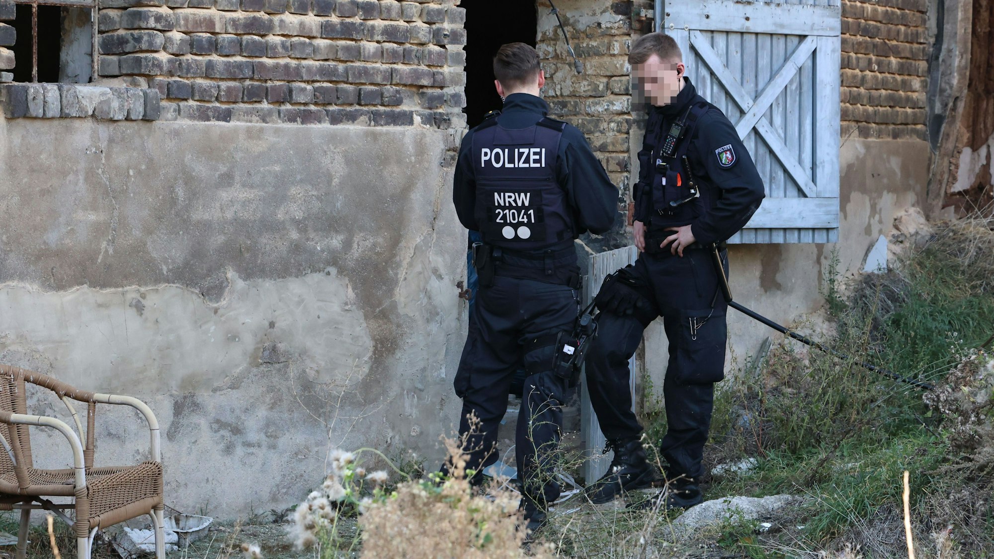 Zwei Polizisten stehen am Eingang einer Halle. Dort wurde eine Cannabisplantage gefunden.