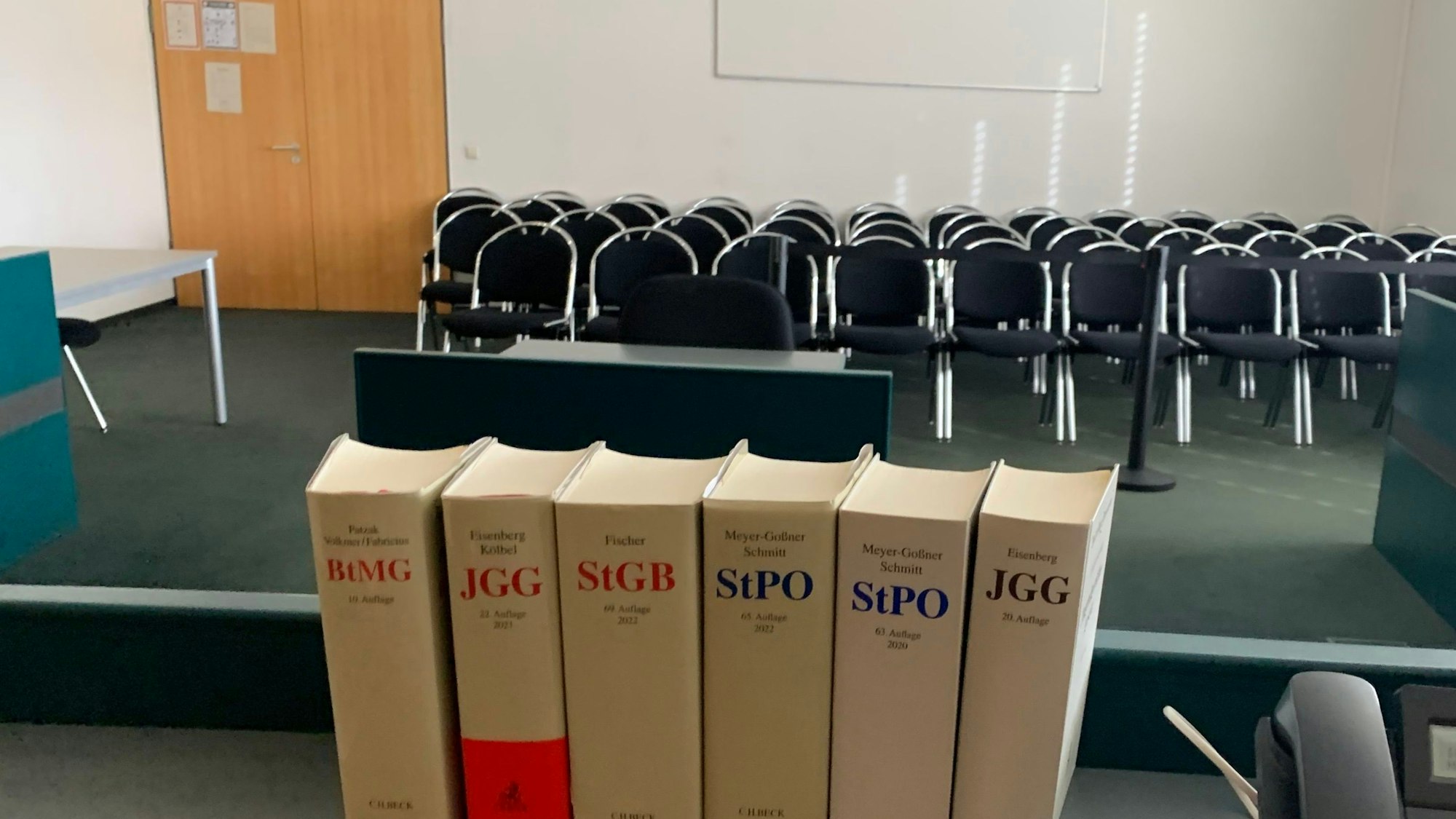 Das Symbolbild zeigt einen Gerichtssaal, im Vordergrund Bücher mit Gesetzestexten.