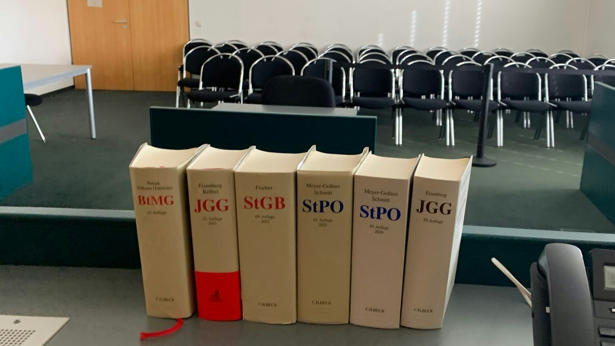Das Symbolbild zeigt einen Sitzungssaal, im Vordergrund Bücher mit Gesetzestexten.