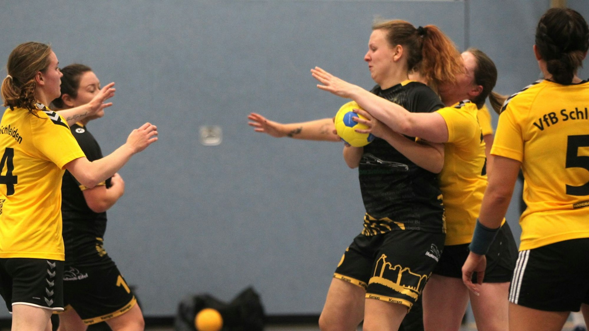 Eine Handballspielerin hat den Ball, eine Gegnerin umklammert sie von hinten.
