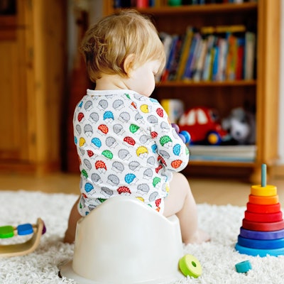 Kleinkind sitzt auf Töpfchen umringt von Spielzeug. Symbolbild.