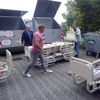 Drei Männer bereiten Pflegebetten für einen Hilfsgütertransport vor.