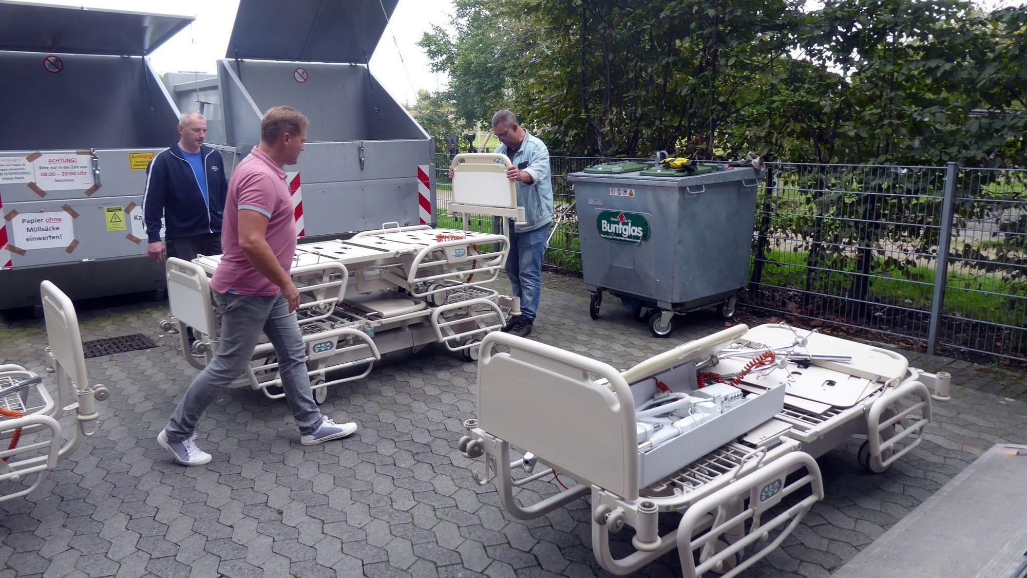 Drei Männer bereiten Pflegebetten für einen Hilfsgütertransport vor.