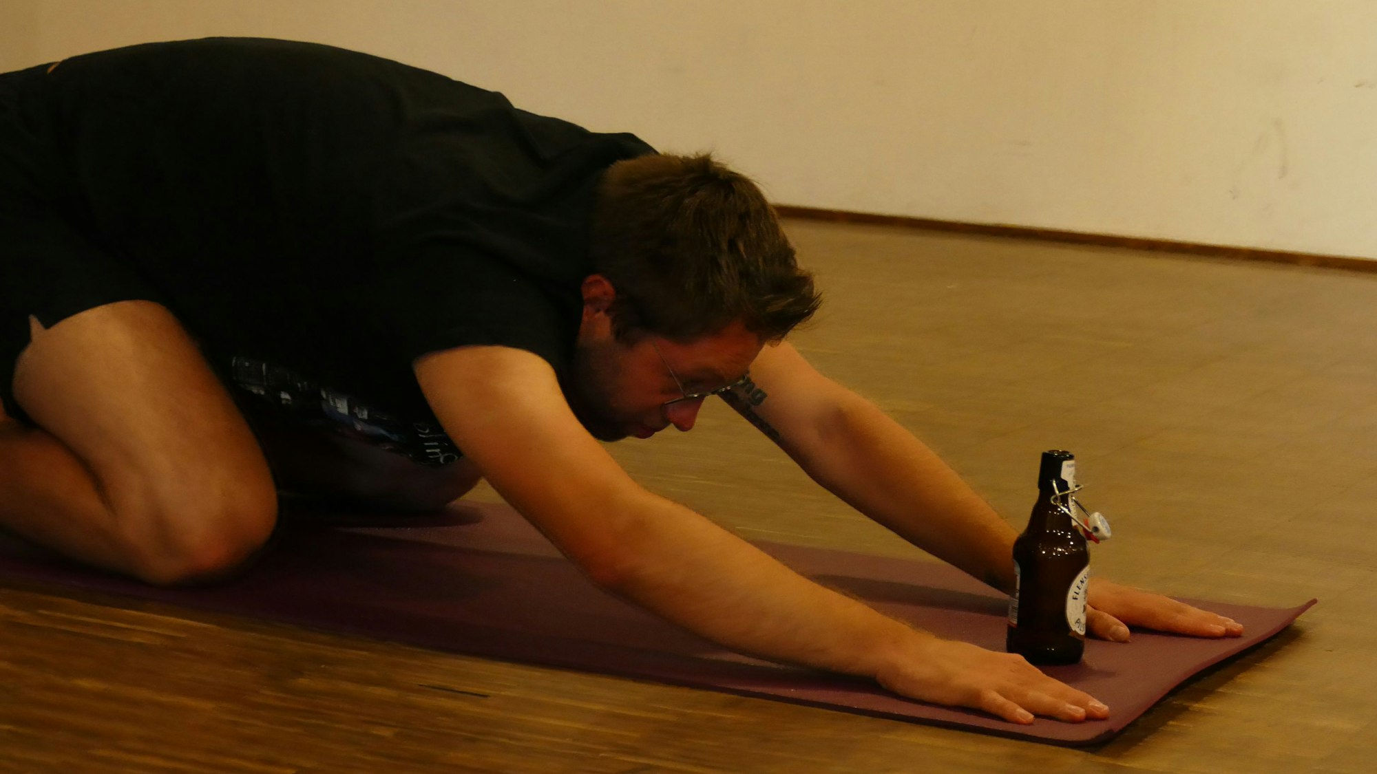 Mann kniet vor einer Flasche Bier