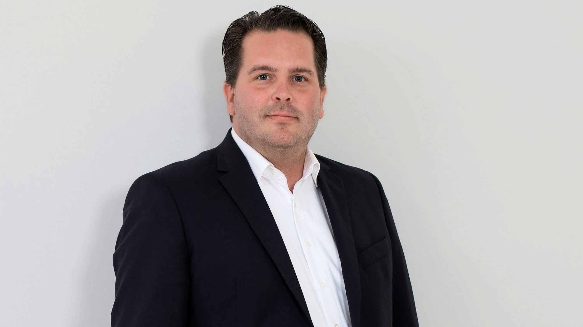 Sebastian Haeger steht vor einer weißen Wand.