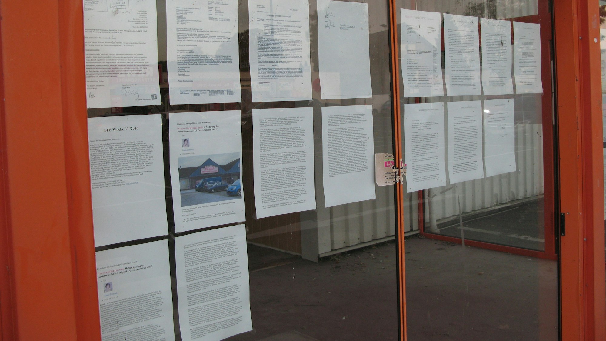 Etliche DIN-A4-Blätter hängen an den Scheiben des alten Baumarkts: alles Dokumente zum Streit um Einzelhandel im Gewerbegebiet.