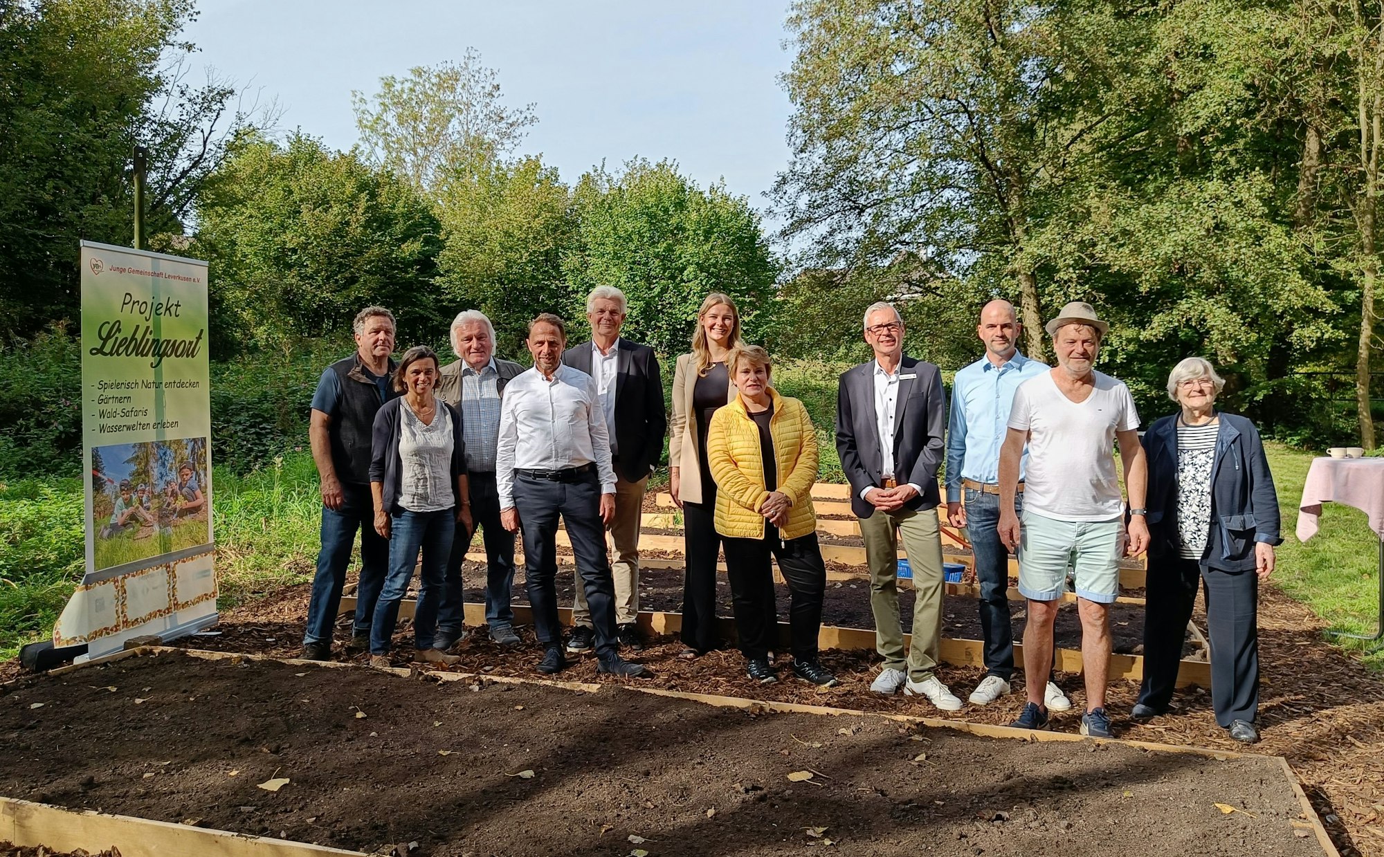 Viele Menschen stehen in einer Reihe zwischen Beeten.