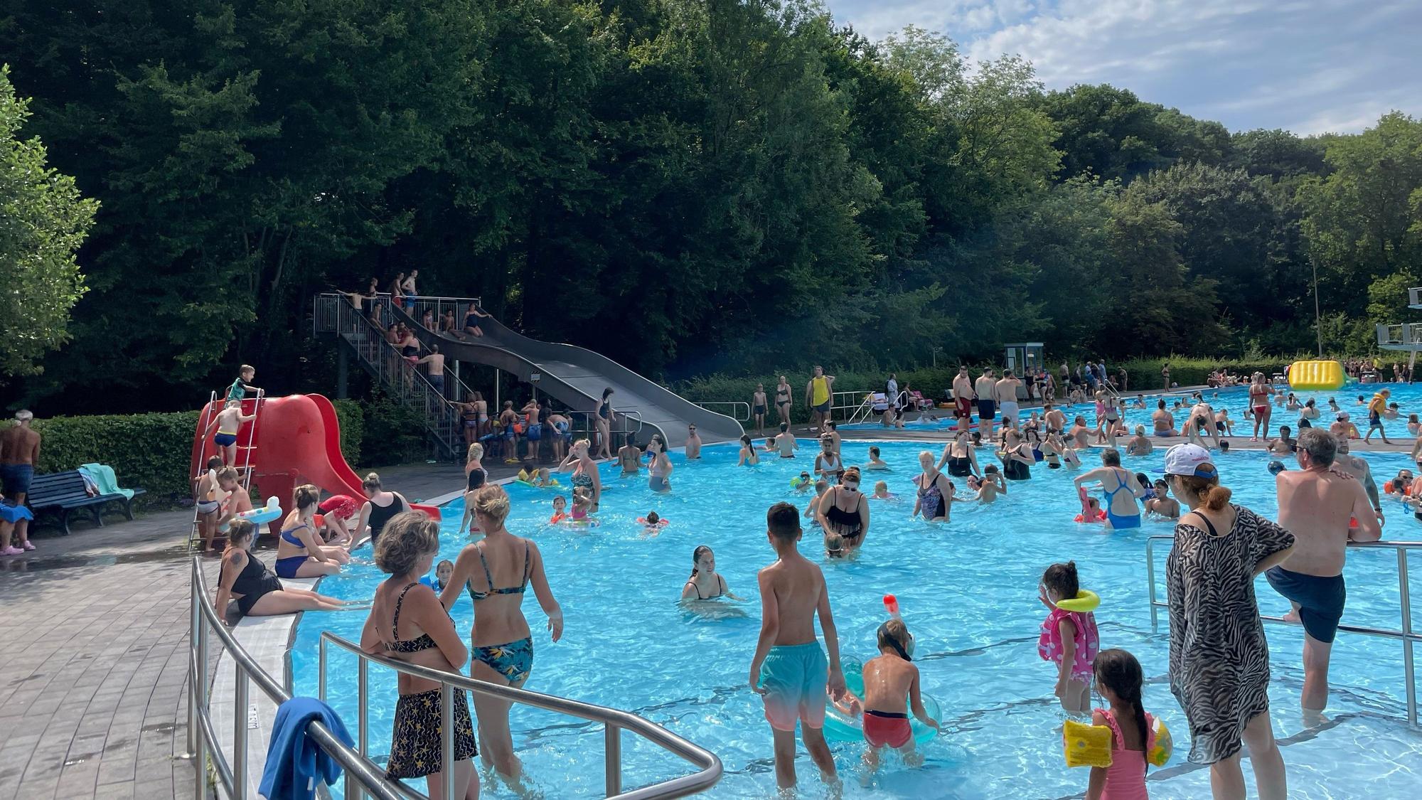 Menschen verschiedenen Alters stehen und schwimmen in einem Becken.