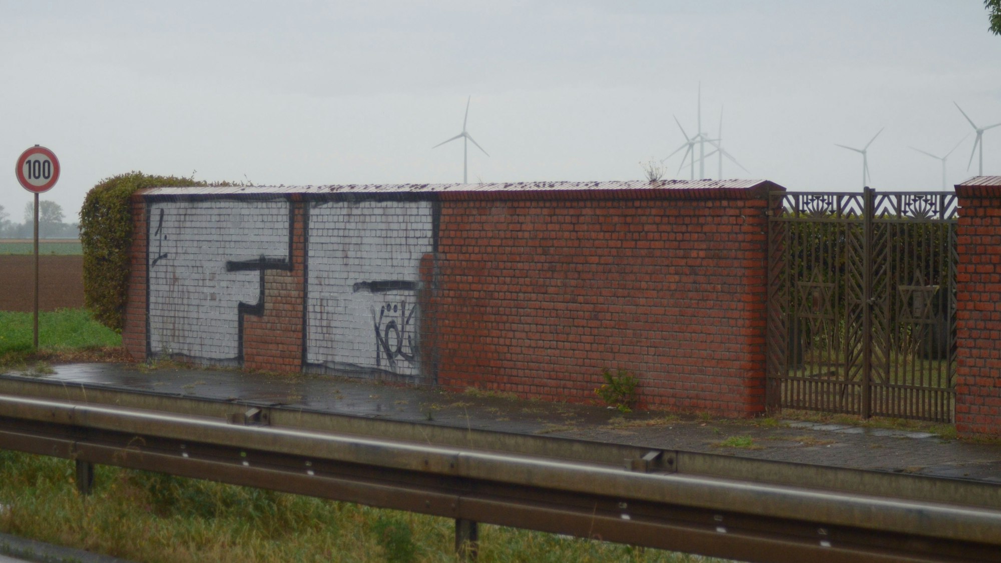 Ein 1.-FC-Köln-Graffito in weißer und schwarzer Schrift, mehrere Quadratmeter groß, auf der Mauer des jüdischen Friedhofs in Euskirchen.