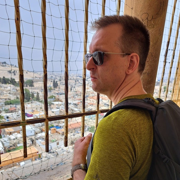 Pastor Oliver Dannenberg steht an der Erlöserkirche in Jerusalem und blickt durch ein Gitter auf die Stadt.