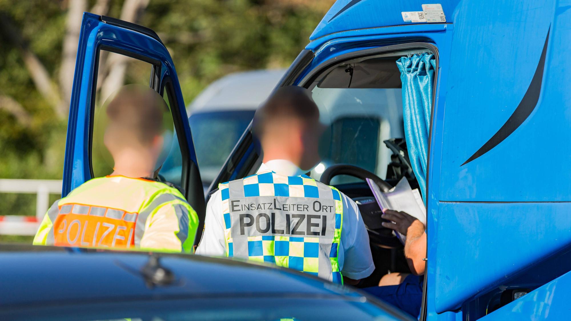 Polizisten kontrollieren das Führerhaus und einen Fahrer eines Lkw auf einer Autobahn. Bei Böblingen auf der A81 hat ein Lkw-Fahrer sein Fahrzeug auf dem Autobahn-Mittelstreifen abgestellt und ein Nickerchen gehalten. (Symbolbild)