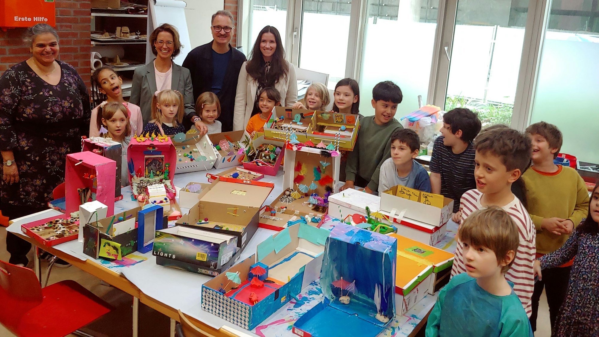 Zu sehen sind mehrere Menschen, die um einen Tisch mit Spielzeug herumstehen.