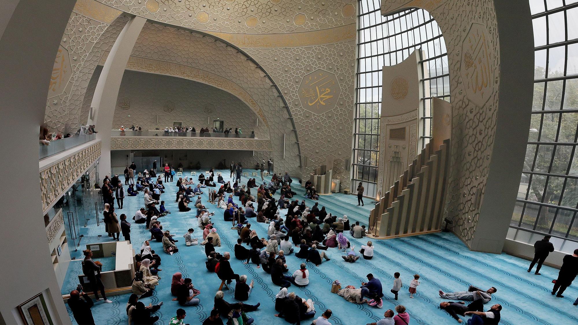 Blick ins Innere: Menschen sitzen auf dem Boden der Moschee