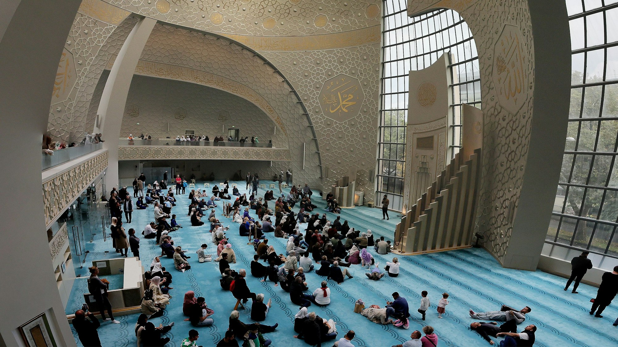 Blick ins Innere: Menschen sitzen auf dem Boden der Moschee