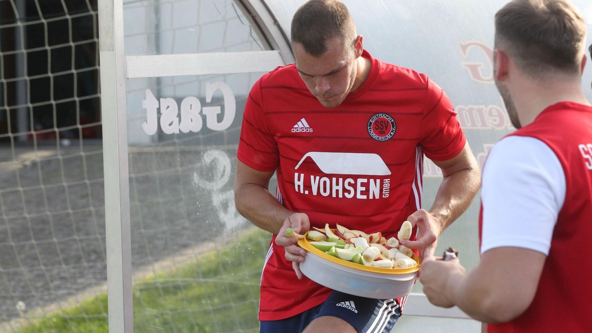Das Bild zeigt zwei Fußballer des SSV Lommersum, wie sie Obst essen – und einen Schokoriegel.