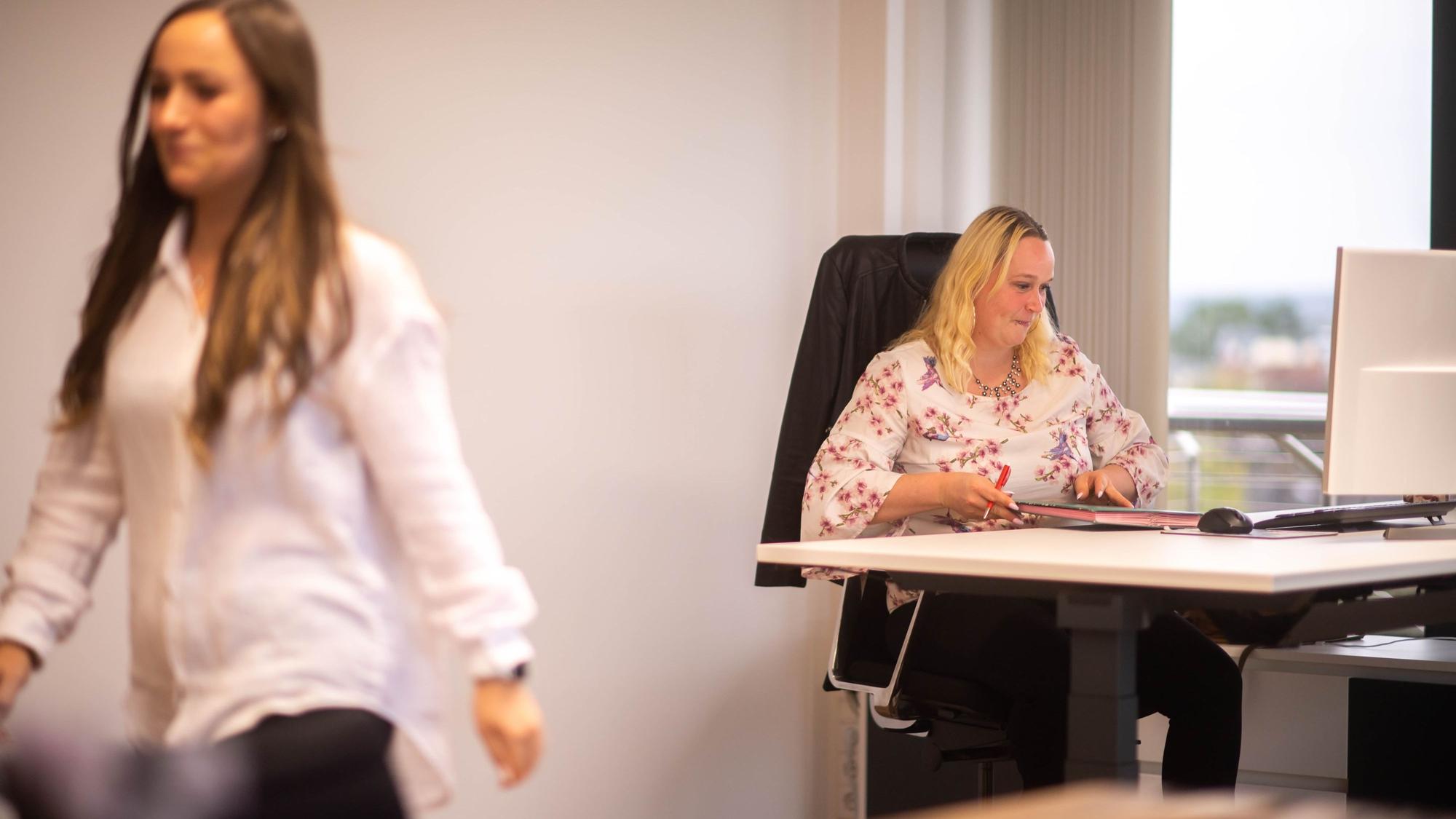 Das Bild zeigt Simone Limbach am Schreibtisch im Kreishaus. Luisa Vogelsberg verlässt gerade das Büro.