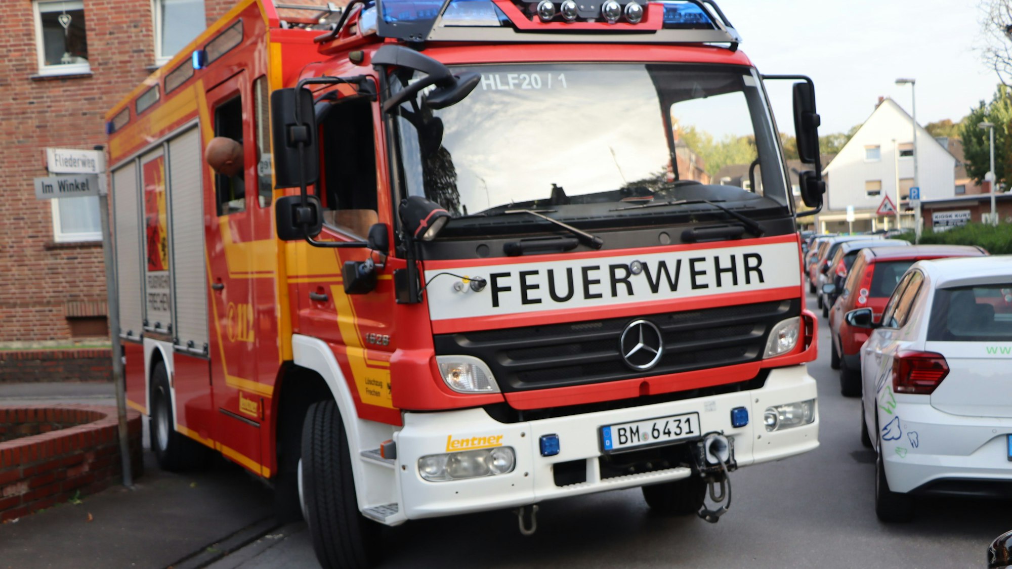 Auf dem Foto ist zu sehen, wie sich ein Feuerwehrauto an den am Straßenrand geparkten Pkw vorbeischiebt.