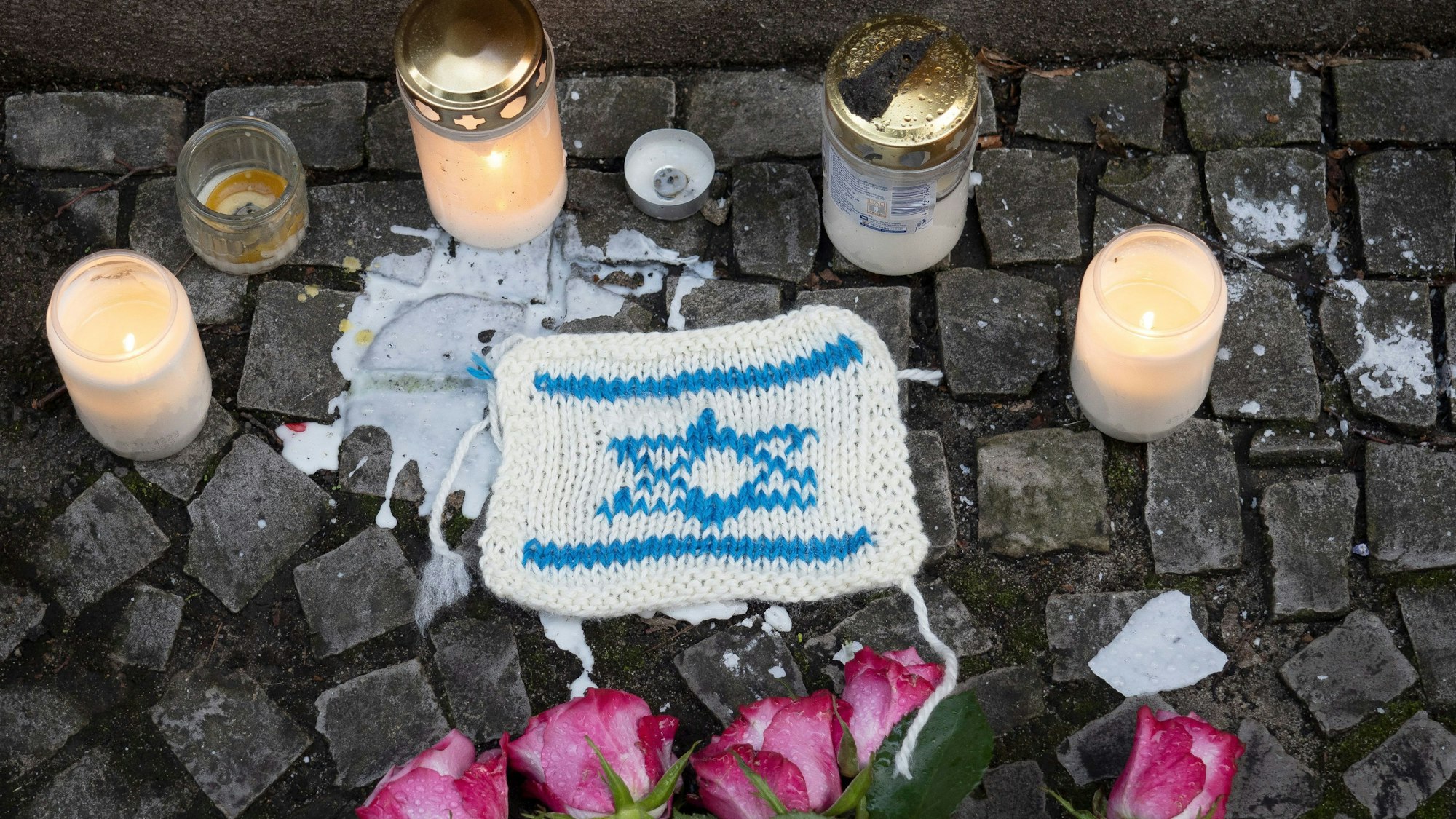 13.10.2023, Berlin: An der jüdischen Synagoge in der Oranienburger Straße stehen Kerzen und ein gestricktes Bildnis der Flagge Israels zum Gedenken an die Opfer des Terrorangriffs der Hamas. Foto: Paul Zinken/dpa +++ dpa-Bildfunk +++