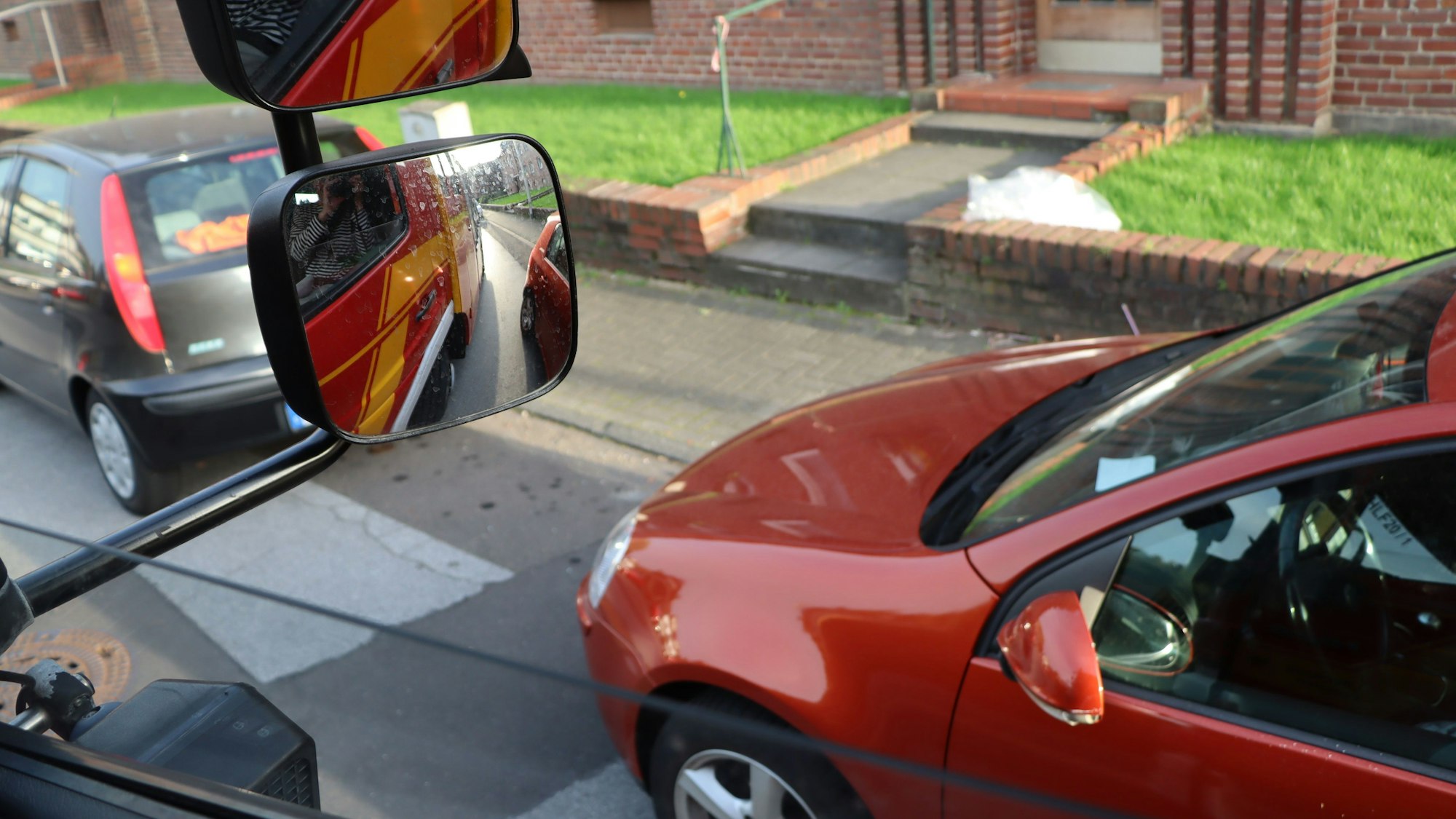 Das Foto zeigt den Blick aus dem Fenster des Feuerwehrwagens und die nah geparkten Fahrzeuge am Straßenrand.