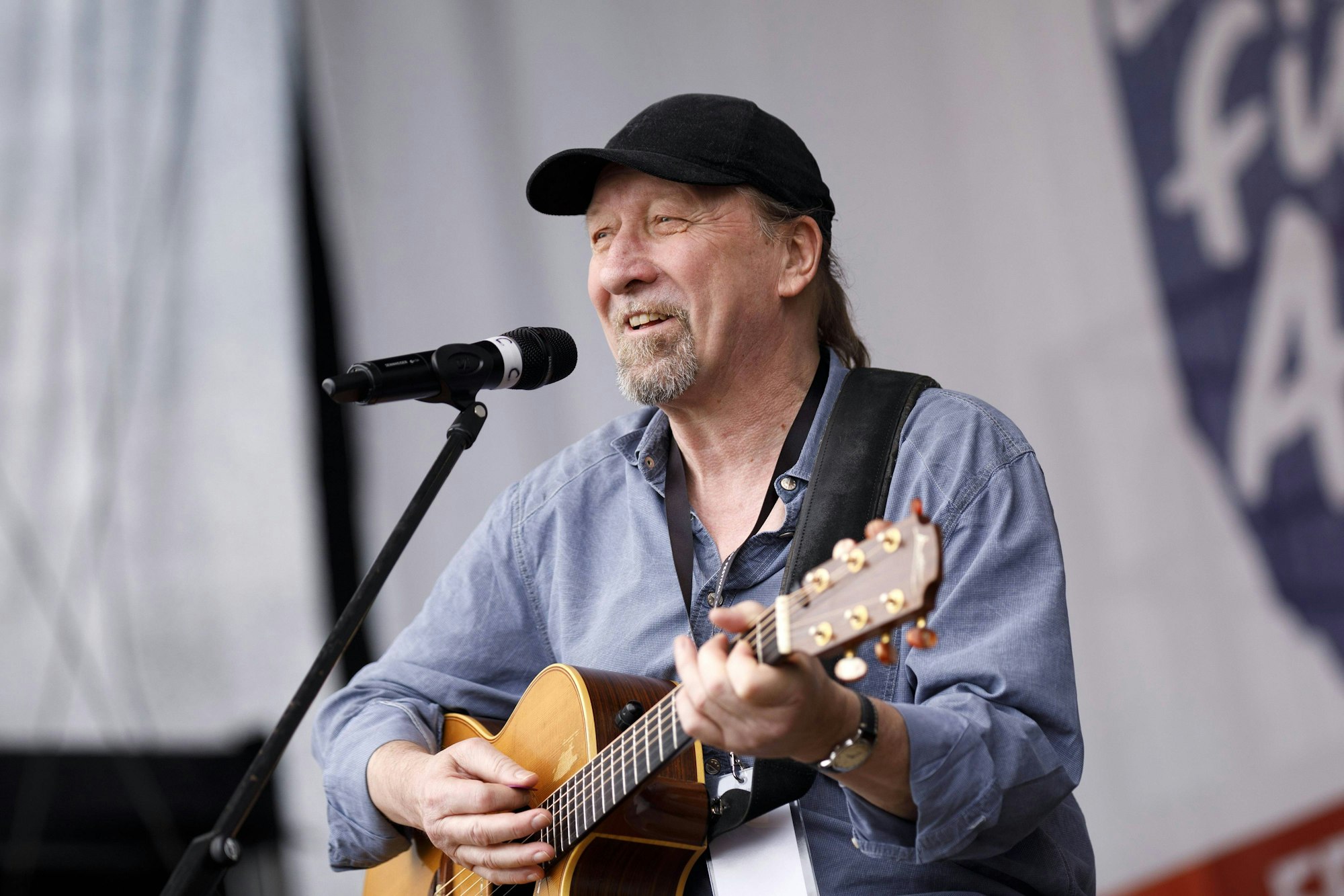 Frank Hocker mit Gitarre vor einem Mikrofon bei einem Auftritt bei einer Kundgebung an der Deutzer Werft im Jahr 2019.