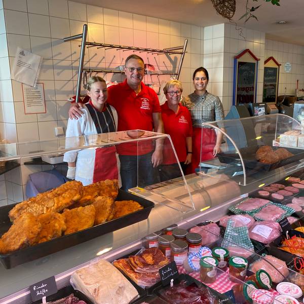 Das Foto zeigt eine Metzgerei mit einer Fleisch- und Wursttheke und vier Personen