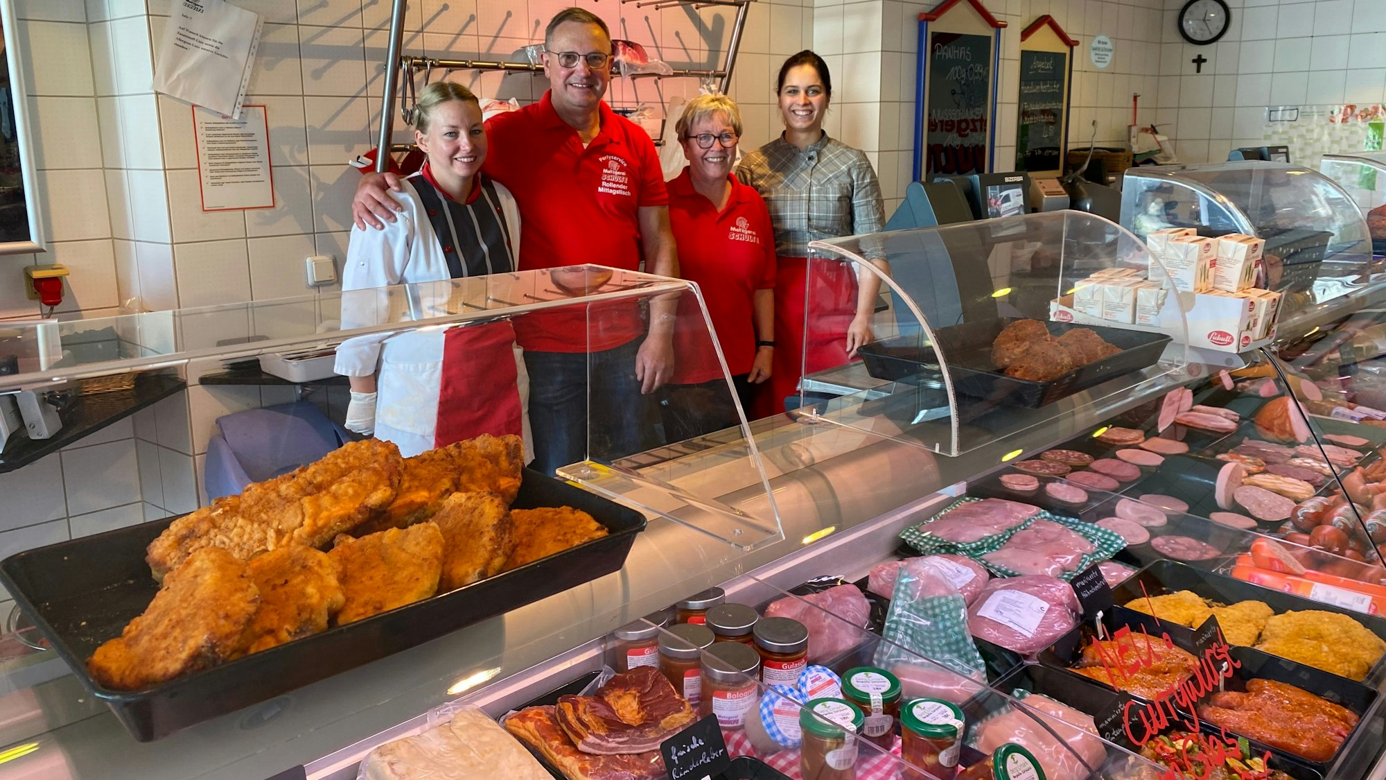 Das Foto zeigt eine Metzgerei mit einer Fleisch- und Wursttheke und vier Personen