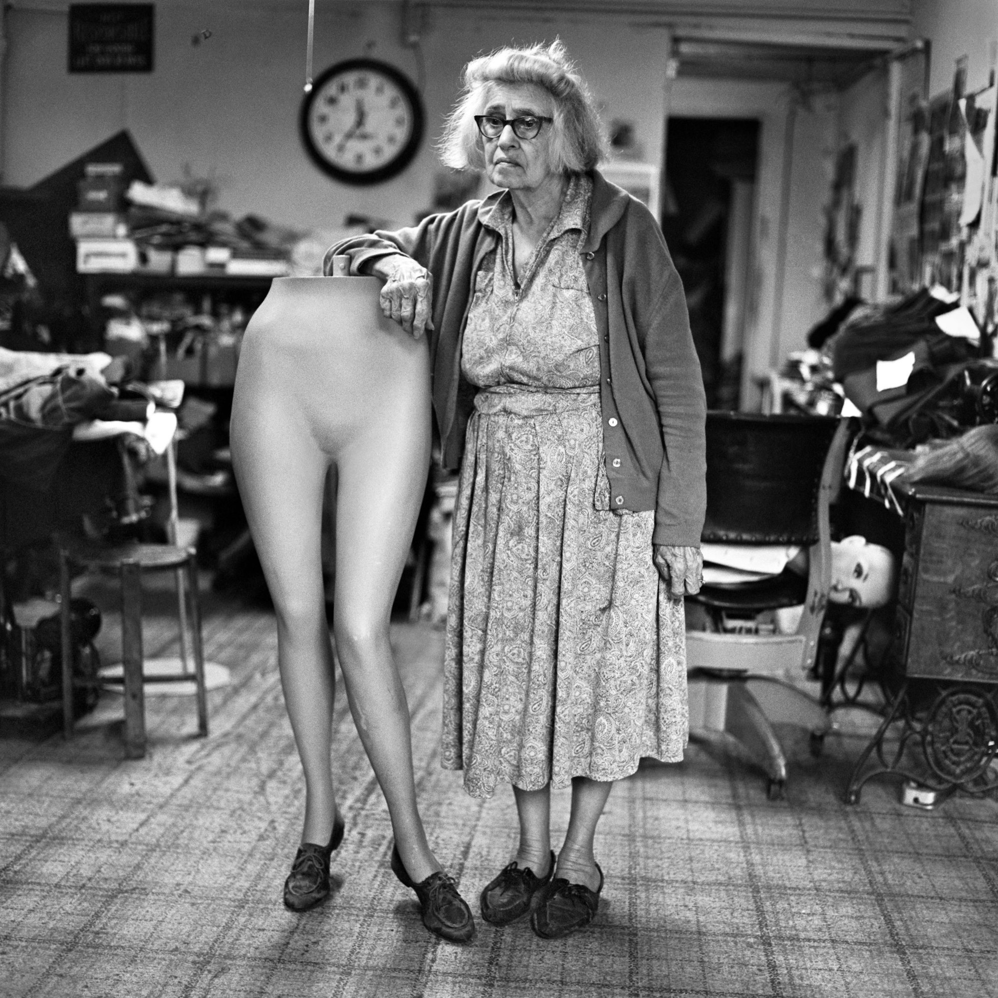 Eine alte Frau posiert mit einer Schneiderpuppe ohne Oberleib.